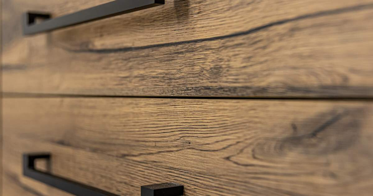 close up view of stained wooden drawers with black handles 